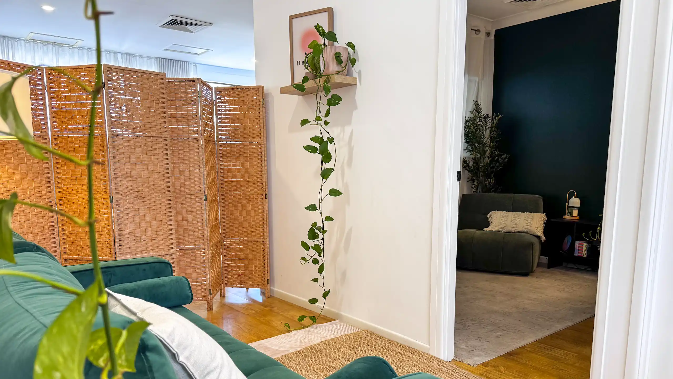 Green velvet sofa and trailing pothos in the calm reception area of Seabreeze Bodywork & Massage in Miami, with a view through to the treatment room