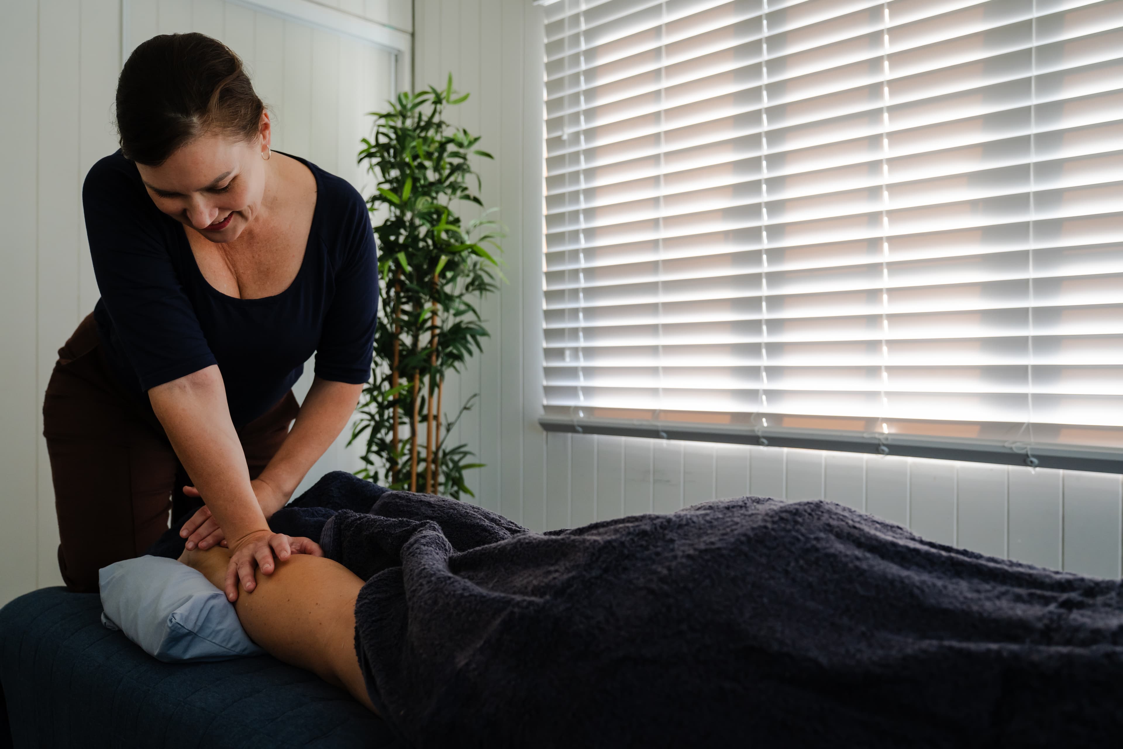 Hands applying trigger point and myofascial release technique to the plantar fascia and sole of the foot, addressing heel pain and foot tightness.